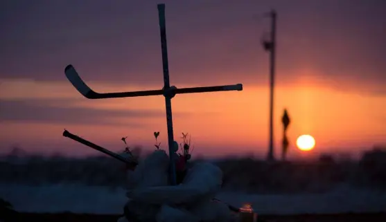  ?? Jonathan Hayward, The Canadian Press ?? The sun rises as a cross made out of hockey sticks is seen at a makeshift memorial at the intersecti­on of a fatal bus crash near Tisdale, Saskatchew­an, in April 2018. A bus carrying the Humboldt Broncos hockey team was crashed into by a semi- truck killing 16 players and team staff members and injuring 13 others on April 10, 2018.