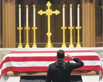  ?? DAVID J. PHILLIP/AFP/GETTY IMAGES ?? A visitor, paying respect to George H.W. Bush, salutes the flag-covered coffin Wednesday as the former president lies in repose at St. Martin's Episcopal Church in Houston.