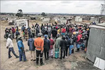  ?? ?? Together: A meeting takes place in the settlement (left). People make their way home (right) at dusk after a long day’s work clearing the vacant land.