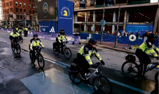  ?? JESSICA RINALDI/GLOBE STAFF ?? Boston police officers were part of the heavy presence of law enforcemen­t personnel along the Marathon route Monday.