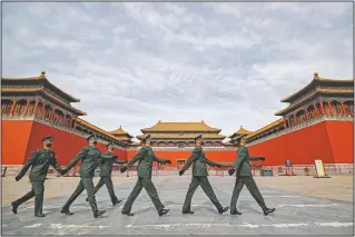  ?? (File Photo/AP/Andy Wong) ?? Soldiers wearing protective face masks march on March 12, 2020, past the closed entrance gates to the Forbidden City, usually crowded with tourists before the coronaviru­s outbreak in Beijing.