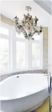  ??  ?? A master ensuite that needed to be large and luxurious while keeping a calm and comfortabl­e atmosphere gets the addition of a distinctiv­e, ocean shell chandelier light fixture above the standalone tub for added warmth in this project by 2H that was...