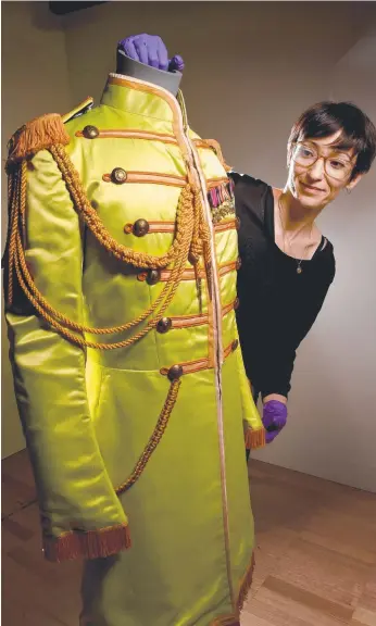  ?? Picture: TONY GOUGH ?? Exhibition manager Ana Martinez checks out John Lennon's Sgt Pepper's suit.