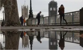  ?? Photograph: Dan Kitwood/Getty Images ?? Members of the public are reflected in a puddle near the Houses of Parliament.