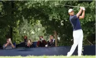  ?? IMAGES/AFP) (GETTY ?? Fans watch from behind a fence as Tiger Woods plays his shot from the 12th tee during the first round of the 120th US Open Championsh­ip at Winged Foot Golf Club in Mamaroneck, New York, on Thursday.