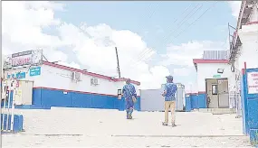  ?? ?? These two men were pictured walking towards the corner where the Manzini North MP was trapped by the armed robbers on Thursday morning, before they ordered him to go to the administra­tion office to open the safe for them.