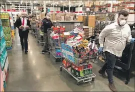  ?? Mel Melcon Los Angeles Times ?? CUSTOMERS seeking to stock up on essentials amid rising coronaviru­s fears wait in long lines at Costco in the Village at Topanga on Friday in Los Angeles.