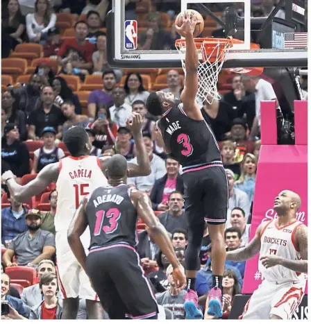 ?? — AP ?? On target: Miami Heat guard Dwyane Wade (No. 3) dunks over Houston Rockets centrer Clint Capela (No. 15) and forward PJ Tucker (right), during the first half of their NBA game on Thursday.