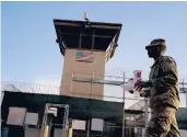  ?? RAMONESPIN­OSA/AP2018 ?? A task force member walks past a detention facility at the Guantanamo Bay U.S. Naval Base.