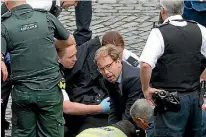  ?? PHOTO: GETTY IMAGES ?? Conservati­ve MP Tobias Ellwood, centre, helps emergency services attend to a police officer who was stabbed outside the Palace of Westminste­r.