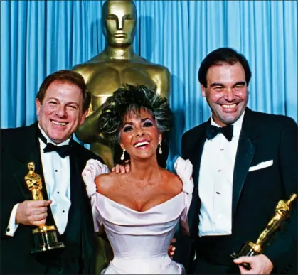  ??  ?? SUCCESS STORY: Oliver Stone, right, and Platoon producer Arnold Kopelson with Elizabeth Taylor at the 1987 Oscars