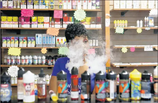  ?? SUZANNE TENNANT/POST-TRIBUNE ?? Co-owner Endia Lardydell vapes and speaks to customers behind the counter at Vapor & More in Merrillvil­le.