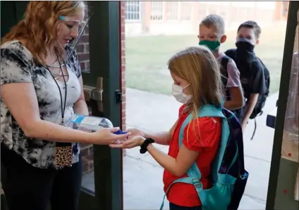  ?? Otero
AP Photo/LM ?? In this Aug. 5 file photo, wearing masks to prevent the spread of COVID19, elementary school students use hand sanitizer before entering school for classes in Godley, Texas.