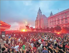  ?? AP ?? Liverpool FC fans ignite flares outside the Liver Building in Liverpool as they celebrate the team’s English Premier League title on Friday.