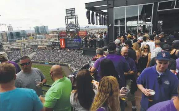  ?? RJ Sangosti, The Denver Post ?? Fans enjoy the view— and the refreshmen­ts— at The Rooftop section of Coors Field. Craft beer flows frequently at The Rooftop, a popular area.