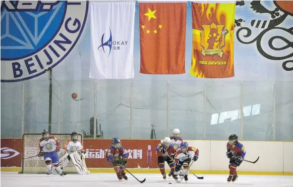  ?? THE ASSOCIATED PRESS FILES ?? Chinese players compete for the puck beneath a Chinese flag during a youth ice hockey tournament in Beijing in February. The NHL sees China as hockey’s next great frontier. With the 2022 Winter Olympics in Beijing, China is eager to step up its game.