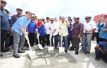  ??  ?? Fadillah (front row, left), Rubiah (front row, second left) and Abdul Karim (front row, third left) seen patching a hole on the Batang Samarahan bridge with concrete to symbolical­ly mark the final stitching works on the bridge yesterday. Also seen are...