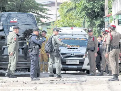  ?? CHANAT ?? Nightmare neighbour Police maintain order outside a building on Soi Charan Sanitwong 34 in Bangkok yesterday after a tenant killed a female building supervisor and threatened to shoot other people. The suspected killer, identified as Piyawat...
