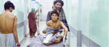  ?? Agence France-presse ?? ↑
A man pushes an injured boy on a stretcher along a hospital corridor in Kandahar on Monday.