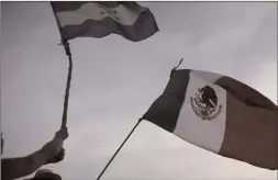 ??  ?? Migrants wave the flags of Honduras and Mexico as they stand stalled after Mexican police blockaded the road to keep them from advancing, outside the town of Arriaga, Chiapas State, Mexico.