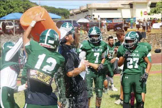  ?? RICK SCHONELY photo ?? Molokai High School coach Mike Kahale is doused with water by his players as the Farmers defeated Lanai on Oct. 5, 2019 to clinch their fifth straight Maui Interschol­astic League eight-player football title. The Farmers have dipped their toe in the pool of the 11-player game, with two preseason games in 2019.