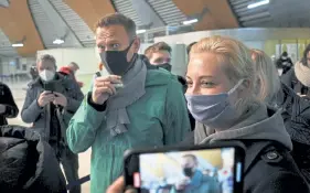  ?? Mstyslav Chernov, The Associated Press ?? Navalny and his wife Yulia stand in line at passport control after arriving at Sheremetye­vo airport. Russia's prison service says the opposition leader was detained after returning from Germany.