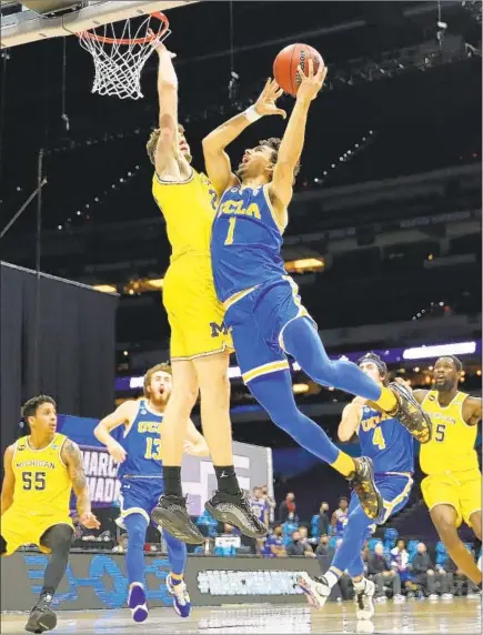  ?? Jamie Squire Getty Images ?? UCLA’S JULES BERNARD drives against Michigan’s Franz Wagner during the first half of the East Regional final at Lucas Oil Stadium in Indianapol­is. The 11th-seeded Bruins survived the final seconds to win their fifth game in a row in the tournament.