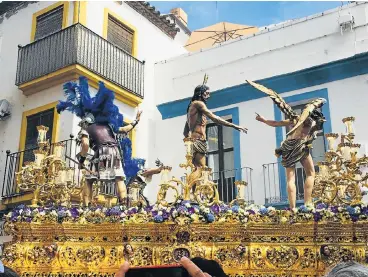  ?? /Madeleine Morrow ?? Faith afloat: A paso featuring a figure of Jesus Christ and Roman centurions glides through the Calle Resolana in Seville, Spain during the Semana Santa (Holy Week). The city is a hive of festivitie­s and a repository of historical relics.