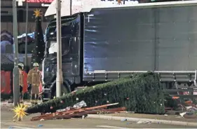  ?? MICHAEL SOHN, AP ?? Firefighte­rs stand beside a truck that ran into a crowded Christmas market Monday in Berlin. Police said it was a deliberate attack.