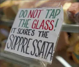  ?? ?? A bit of humor is taped to the meat display case at Donatelli’s. Soppressat­a is a type of Italian salami.
