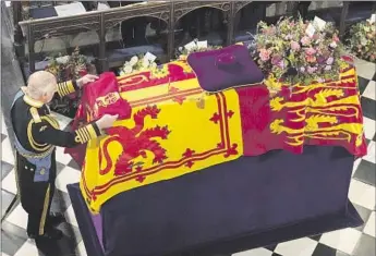  ?? Jonathan Brady Pool Photo ?? KING CHARLES III places a flag called the Queen’s Company Camp Color of the Grenadier Guards on the coffin. The eight pallbearer­s were from the Queen’s Company, 1st Battalion Grenadier Guards.