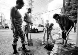  ?? TAYLOR/MULTIMEDIA PHOTO EDITOR GLADSTONE ?? From left: Little North Street residents Sharon Tucker, Devon Myers and Verna Jones look on as 71-year-old Andral Johnson loosens the dirt and silt for removal during a drain-cleaning exercise at the intersecti­on of North Street and Johns Lane in Kingston on November 26.