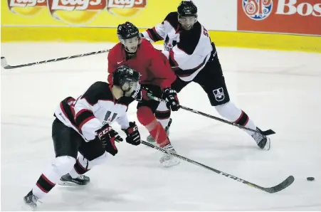  ?? ADRIAN LAM, TIMES COLONIST ?? Canada’s Alex Formenton, middle, fights for the puck with U Sports all-stars forwards Marcus McIvor, left, and Jacob Sweeney during exhibition action at The Q Centre on Wednesday night. Team Canada won 3-2 in a shootout.