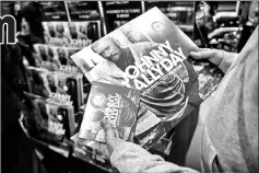  ?? — AFP photo ?? A fan holds copies of Johnny Hallyday upon the midnight release of his posthumous album at the Fnac Champs Elysees store in Paris on Friday.