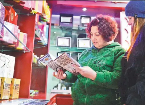  ??  ?? Visitors from Kazakhstan read the introducti­on for specialist­s in a store in Gansu province.