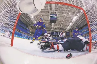  ?? HARRY HOW/POOL PHOTO VIA AP ?? Erika Grahm, left, of Sweden, shoots the puck past South Korea’s goalie Shin So-jung of the combined Koreas team Tuesday at the 2018 Winter Olympics in Gangneung, South Korea. Sweden won 6-1. The team lost by a combined score of 28-2 and was rarely competitiv­e.