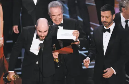  ?? Chris Pizzello / Associated Press 2017 ?? Jordan Horowitz (left), producer of “La La Land,” shows the envelope naming “Moonlight” the best picture winner as Warren Beatty and Jimmy Kimmel look on at last year’s Oscars ceremony in Los Angeles. Steps have been taken to avoid a repeat.
