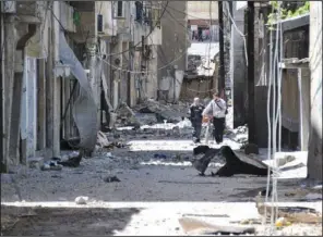  ??  ?? SHELLING: Syrians walk in destroyed alley damaged from Syrian army forces shelling on Saturday at Bab Sbaa neighborho­od in Homs province, central Syria. Opposition activists have said observers appear to make a difference in areas where they stay for...