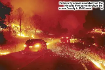  ?? AP ?? Embers fly across a roadway as the Kincade Fire burns through Sonoma County in California.