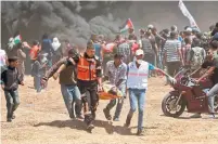  ?? MAHMUD HAMS/AFP/GETTY IMAGES ?? Palestinia­ns carry a demonstrat­or injured during the clashes.