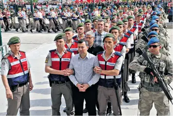  ??  ?? Soldiers accused of involvemen­t in last year’s attempted coup in Turkey are heavily guarded outside court in Sincan yesterday
