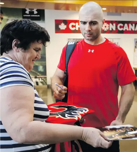  ?? JEFF MCINTOSH/THE CANADIAN PRESS ?? The Calgary Flames’ Mark Giordano signs autographs before training camp in Calgary on Wednesday.