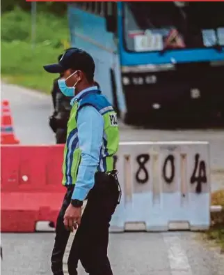  ?? PIC BY ASYRAF HAMZAH ?? A policeman questionin­g a motorcycli­st at a roadblock near Batu 21 Sungai Lui in Hulu Langat yesterday.