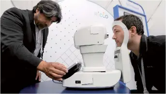  ??  ?? Jorge Cuadros (left) gives a demonstrat­ion of a robotic retinal camera to a reporter at the Google I/O conference in Mountain View, California. — IC