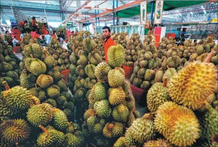  ?? ATHIT PERAWONGME­THA / REUTERS ?? A durian vendor waits for customers at a market in Bangkok.