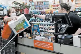  ?? CHARLIE RIEDEL/AP ?? A plastic panel separates a shopper from a clerk Thursday in Overland Park, Kansas.