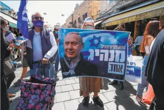  ?? Emmanuel Dunand / AFP / Getty Images ?? Supporters of Israel’s Likud party raise a banner depicting Prime Minister Benjamin Netanyahu during a rally Friday at market in Jerusalem. Voters head to the polls Tuesday.