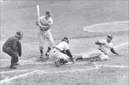  ?? John Rooney Associated Press ?? JACKIE ROBINSON of the Dodgers steals home under the tag of New York catcher Yogi Berra in the ninth inning of the 1955 World Series opener in Yankee Stadium.