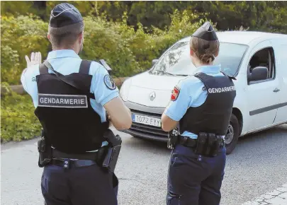  ?? AP PHOTOS ?? DRAGNET: French police officers, above, check a car at the border crossing between Spain and France yesterday as they search for terror suspect Younes Abouyaaquo­ub.