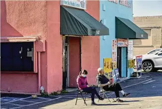  ?? Philip Cheung/For The Washington Post ?? People sit in a parking lot on Tuesday in Monterey Park, Calif., near the Star Ballroom Dance Studio, site of a Jan. 21 gun attack that killed 11.